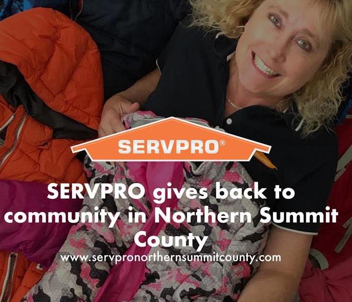 Orange SERVPRO  house logo on image with staff member in background with coats. 